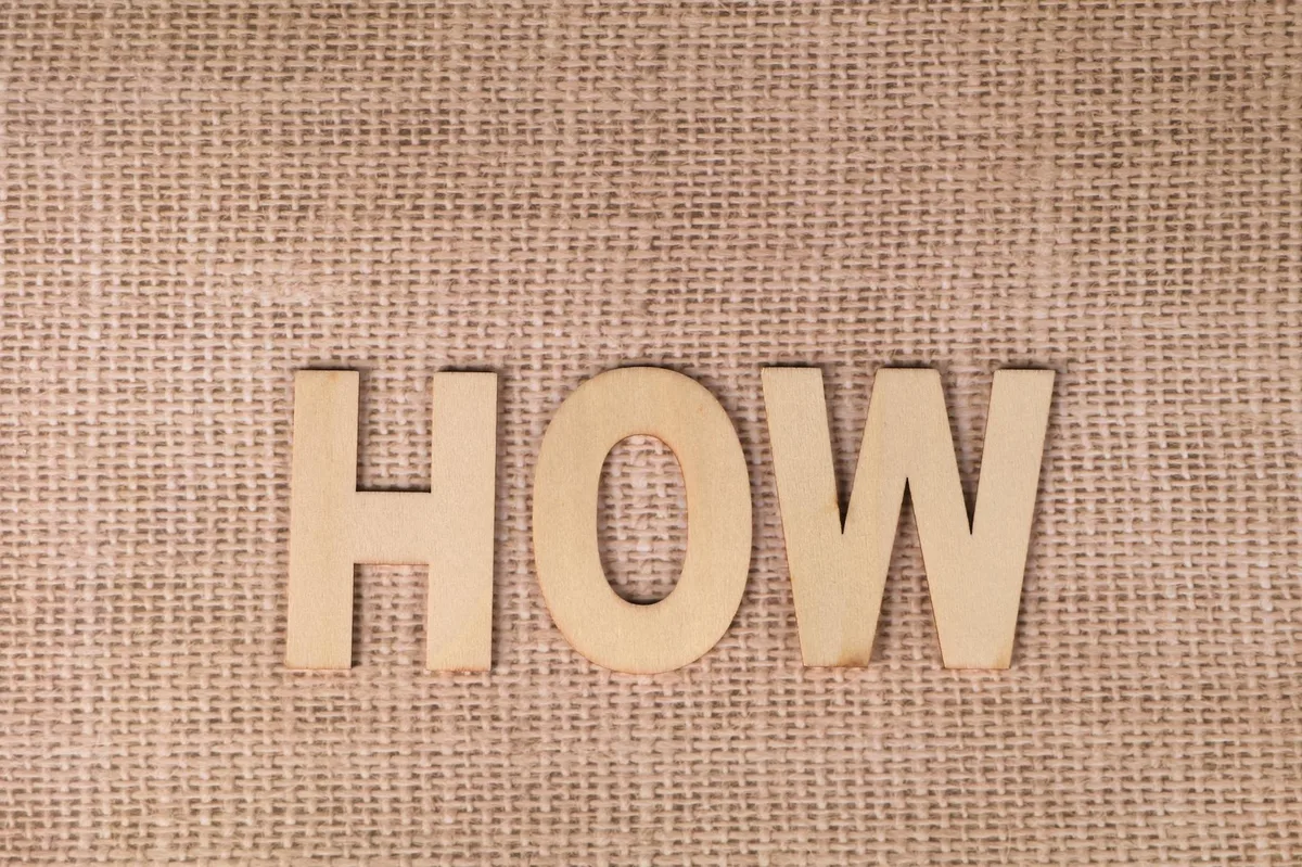 cách tạo backlink tự nhiên — Word 'HOW' formed with wooden letters on textured burlap surface.